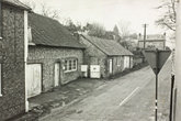 Falmer village looking up opposite Slark's garage, back of triangular roadside on left, flint buildings on right