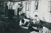 Brian sitting in the back garden with his parents and friend reading with a view of the back garden and washing on the line